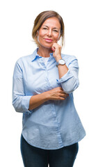 Wall Mural - Middle age senior hispanic woman over isolated background with hand on chin thinking about question, pensive expression. Smiling with thoughtful face. Doubt concept.