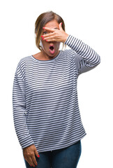 Sticker - Middle age senior hispanic woman over isolated background peeking in shock covering face and eyes with hand, looking through fingers with embarrassed expression.