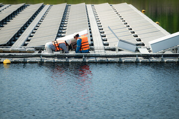 Both of technicians are currently evaluating and repairing the transmission terminals for electricity generated by solar energy in a floating solar power system.