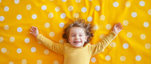 Criança Feliz Deitada Em Um Tapete Amarelo Com Bolinhas Brancas