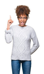 Wall Mural - Beautiful young african american woman wearing winter sweater over isolated background pointing finger up with successful idea. Exited and happy. Number one.