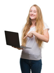 Sticker - Blonde teenager woman using computer laptop very happy pointing with hand and finger