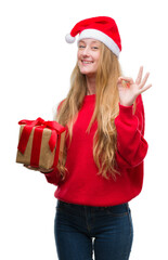 Poster - Blonde teenager woman wearing santa claus hat doing ok sign with fingers, excellent symbol