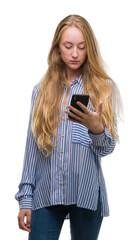 Sticker - Blonde teenager woman using smartphone with a confident expression on smart face thinking serious