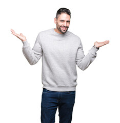 Young handsome man wearing sweatshirt over isolated background Smiling showing both hands open palms, presenting and advertising comparison and balance