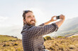© Stefanie - Portrait of man with beard smiling in the camera while taking selfy while hiking in the hills. Franschoek, South Africa