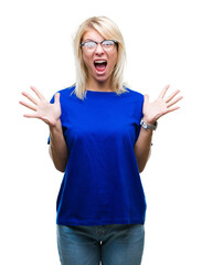 Wall Mural - Young beautiful blonde woman wearing glasses over isolated background celebrating crazy and amazed for success with arms raised and open eyes screaming excited. Winner concept