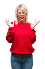 Wall Mural - Young beautiful blonde woman wearing sweater and glasses over isolated background celebrating mad and crazy for success with arms raised and closed eyes screaming excited. Winner concept