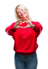 Sticker - Young beautiful blonde woman wearing sweater and glasses over isolated background smiling in love showing heart symbol and shape with hands. Romantic concept.