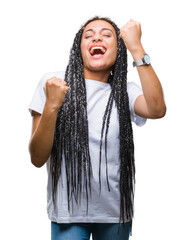 Wall Mural - Young braided hair african american girl over isolated background very happy and excited doing winner gesture with arms raised, smiling and screaming for success. Celebration concept.