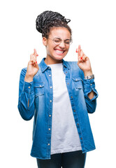 Poster - Young braided hair african american girl wearing glasses over isolated background smiling crossing fingers with hope and eyes closed. Luck and superstitious concept.