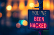 Neon sign saying You've Been Hacked at night with bokeh lights