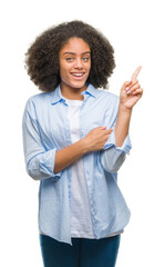 Sticker - Young afro american woman over isolated background with a big smile on face, pointing with hand and finger to the side looking at the camera.