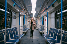 A Young Woman Rides In A Modern Subway Car With A Phone In Her Hands.