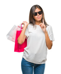 Sticker - Young asian woman holding shopping bags on sales over isolated background serious face thinking about question, very confused idea