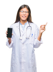 Sticker - Young asian doctor woman holding smartphone over isolated background very happy pointing with hand and finger to the side