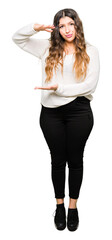 Poster - Young beautiful woman wearing white sweater gesturing with hands showing big and large size sign, measure symbol. Smiling looking at the camera. Measuring concept.