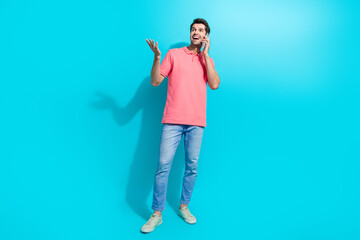 Poster - Full length body photo of young laughing guy wear pink t shirt phone call look novelty conversation isolated on aquamarine color background