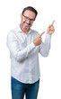 © Krakenimages.com - Handsome middle age elegant senior business man wearing glasses over isolated background smiling and looking at the camera pointing with two hands and fingers to the side.