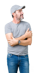 Wall Mural - Handsome middle age hoary senior man wearing sport cap over isolated background smiling looking to the side with arms crossed convinced and confident