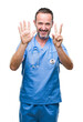 © Krakenimages.com - Middle age hoary senior doctor man wearing medical uniform over isolated background showing and pointing up with fingers number seven while smiling confident and happy.