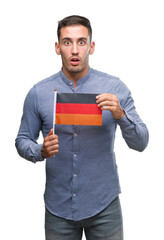 Sticker - Handsome young man holding a flag of Germany scared in shock with a surprise face, afraid and excited with fear expression