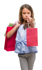 Poster - Brunette hispanic girl holding shopping bags pointing with finger to the camera and to you, hand sign, positive and confident gesture from the front