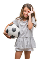 Poster - Brunette hispanic girl holding soccer football ball with happy face smiling doing ok sign with hand on eye looking through fingers