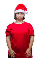 Poster - Young adult woman with down syndrome wearing christmas hat over isolated background with serious expression on face. Simple and natural looking at the camera.