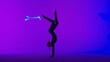 © kinomaster - Female gymnast isolated on laser blue neon studio background. Girl dancer showing gymnastic elements on the floor.
