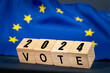 European Union vote, the word Vote on wooden blocks against the background of the EU flag, the concept of voting and taking part in the European elections