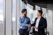 © Liubomir - Two professional businessmen shaking hands in a modern office, symbolizing partnership, collaboration, and successful business agreement.