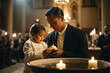 Baptismal Blessings - A priest gently holds an infant over the baptismal font, while the soft glow of candlelight and the sprinkling of holy water.
