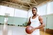 © Marko Geber - Portrait of a young fit man holding basketball at indoor court