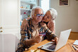 © Marko Geber - Senior couple online shopping with credit card at home