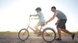 © maxximmm - family play in the park. father teaching son to ride a bike. happy family kid dream concept. son learn to ride a bike silhouette. father supporting child son riding bike summer in the sunset park