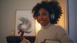 © stockbusters - Cheerful model dancing headphones evening interior. African girl listening music