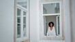 © stockbusters - Positive lady looking outdoors at window place. African woman watching cityscape