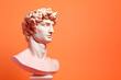 Gypsum statue of David's head, Michelangelo's David statue plaster copy on peach fuzz color of the year 2024 background. Ancient Greek sculpture, statue of hero, copy space for text