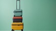 Stacked colorful suitcases against mint green background ready for travel