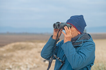 A man bird-watching with binoculars.