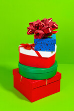 A Colorful Stack Of Various Shaped Gift Boxes With A Glittering Bow On A Bright Green Background