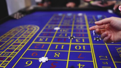 Wall Mural - Vibrant casino table with roulette in motion, with casino chips, tokens, the hand of croupier, dollar money and a group of gambling rich people playing bet, blue poker table and deck of cards