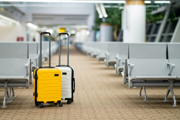 Wall Mural - Two suitcases in an empty airport hall, traveler cases in the departure airport terminal waiting for the area, vacation concept, blank space for text message or design