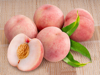 Wall Mural - fresh white peach fruits with leaves on bamboo mat, korean white peach on wooden bamboo table.