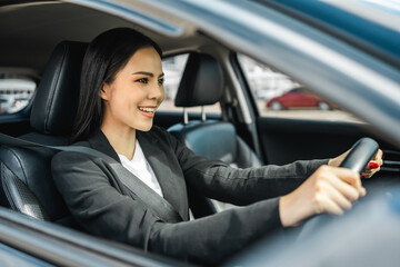 Wall Mural - Young beautiful asian business women getting new car. She very happy and excited. Smiling female driving vehicle on the road on a bright day with sun light. Business woman buying driving new car