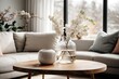 Modern living room's minimalist and Scandinavian design is showcased through a wooden coffee table holding a vase with a blossoming twig. A white sofa adorned with pillows is positioned against the wi