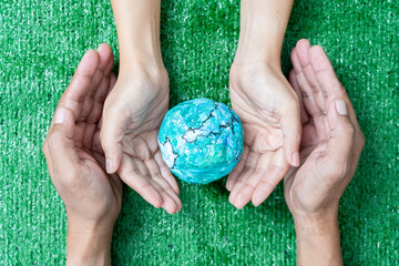 Wall Mural - environment earth day in the hands holding green earth on bokeh green background, saving environment