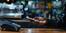 Close up of a African American hand paying bill with credit card contactless payment on smartphone in cafe, scanning on a card machine. Electronic payment. Banking and NFC wireless technology concept