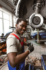 Wall Mural - African male auto-mechanic repairing car brakes under the car in auto service